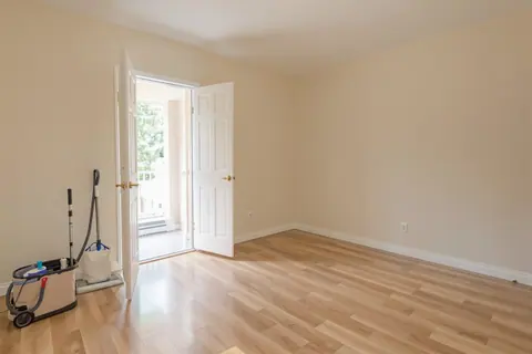 An empty rental unit mid-turnover, cleaning equipment beside the open door